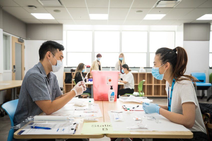 Two School of Pharmacy students sit across from one another as they practice filling syringes to administer medication